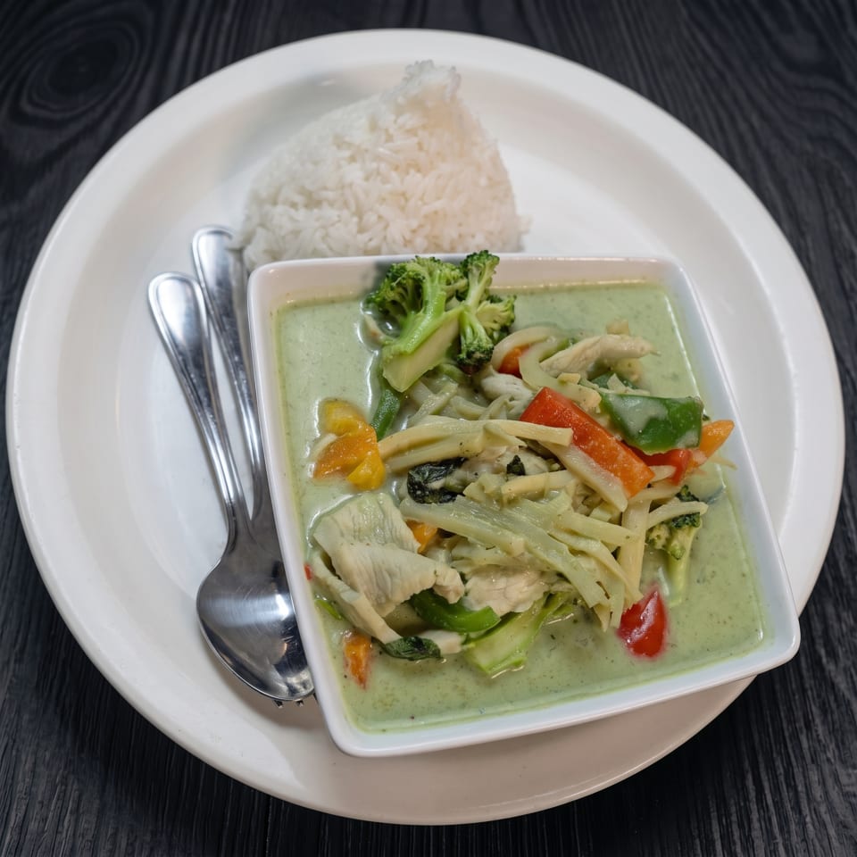 Green curry with chicken, bamboo shoots, broccoli, and peppers, served with white rice.